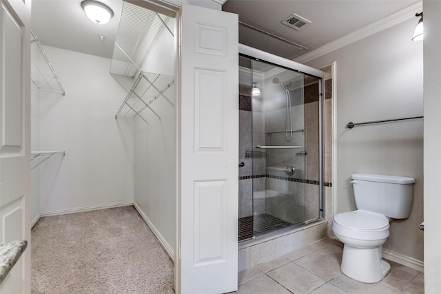 bathroom featuring a shower with door, ornamental molding, tile patterned flooring, and toilet