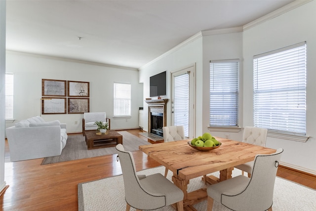 dining space with ornamental molding and light hardwood / wood-style flooring