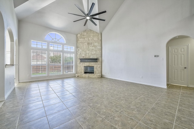 unfurnished living room featuring high vaulted ceiling, ceiling fan, light tile patterned floors, and a stone fireplace