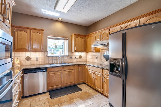 kitchen with appliances with stainless steel finishes, tasteful backsplash, a textured ceiling, and sink