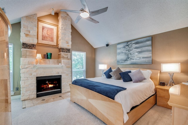 carpeted bedroom featuring vaulted ceiling, a textured ceiling, ceiling fan, and a stone fireplace