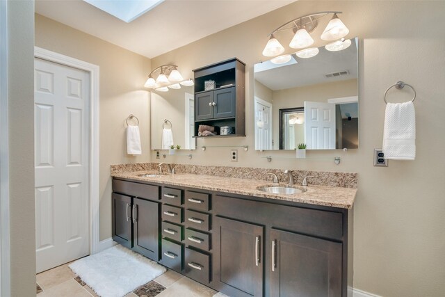 bathroom featuring tile patterned flooring, a skylight, and vanity