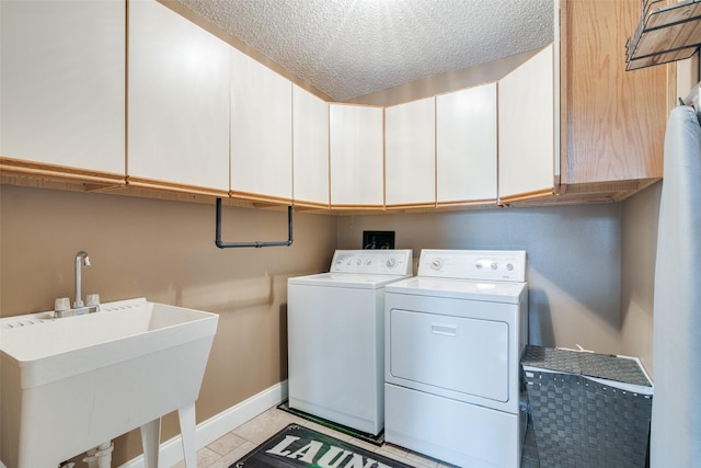 clothes washing area featuring a textured ceiling, cabinets, washer and dryer, light tile patterned flooring, and sink