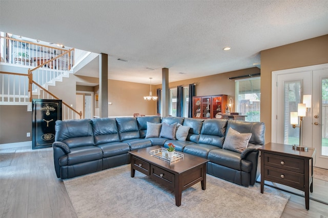 living room with light hardwood / wood-style floors, a notable chandelier, and a textured ceiling