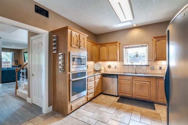 kitchen featuring stainless steel appliances, sink, a wealth of natural light, and tasteful backsplash