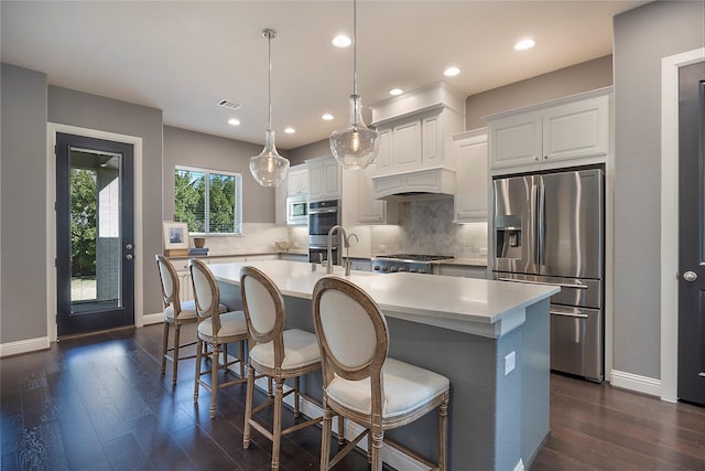 kitchen with hanging light fixtures, white cabinetry, stainless steel appliances, and a kitchen island