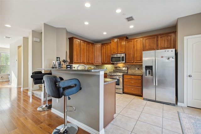 kitchen featuring stainless steel appliances, sink, a kitchen breakfast bar, kitchen peninsula, and decorative backsplash