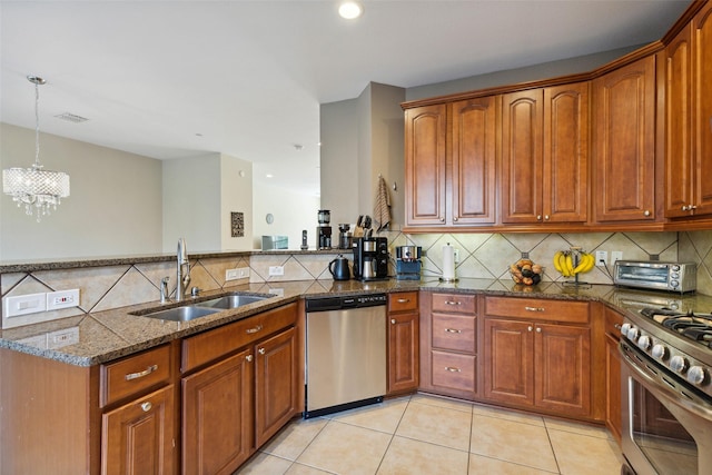 kitchen with sink, dark stone countertops, light tile patterned floors, pendant lighting, and appliances with stainless steel finishes