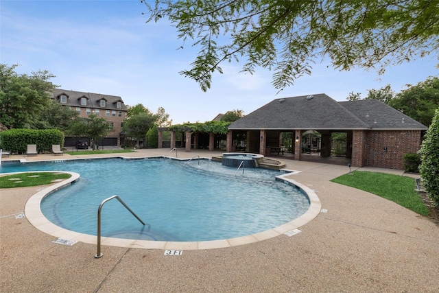 view of pool featuring a hot tub, pool water feature, and a patio area