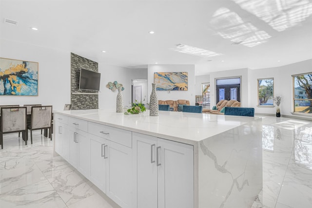 kitchen with a kitchen island, white cabinets, and light stone counters