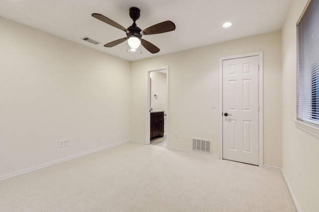 unfurnished bedroom featuring ceiling fan, ensuite bath, and light carpet