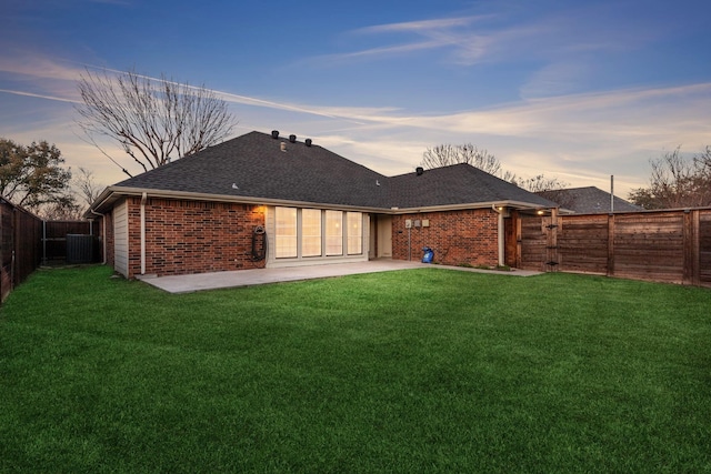 back house at dusk with a patio area and a yard