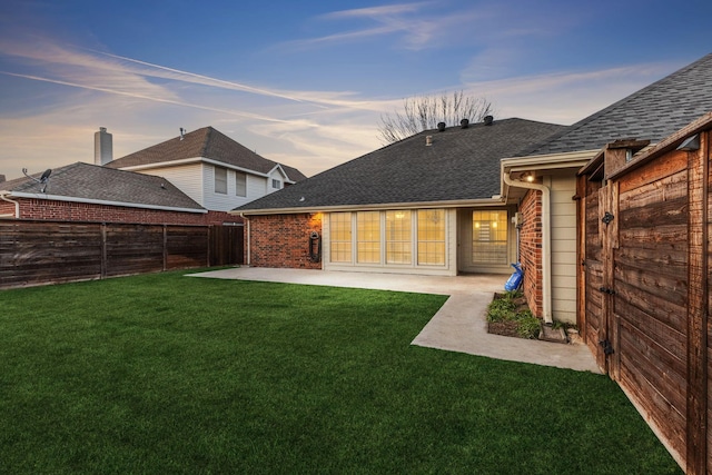 back house at dusk with a yard and a patio area