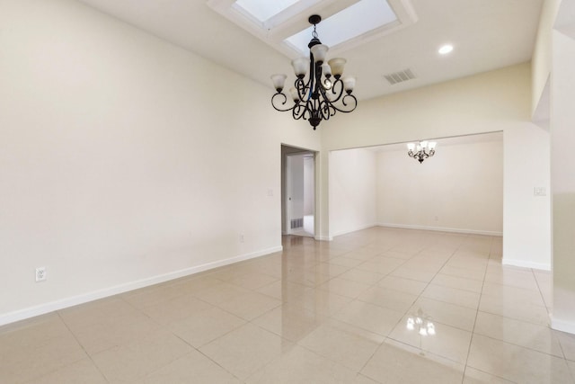 tiled spare room featuring a skylight and a chandelier