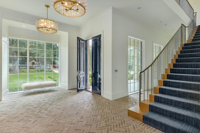 entryway with an inviting chandelier and crown molding