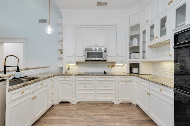 kitchen with black appliances, light stone countertops, pendant lighting, white cabinets, and sink