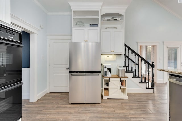 kitchen with light stone countertops, white cabinetry, crown molding, and appliances with stainless steel finishes