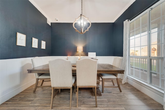 dining space with a wainscoted wall, ornamental molding, and wood finished floors