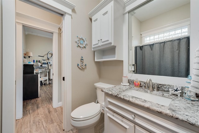 bathroom with toilet, vanity, and hardwood / wood-style floors