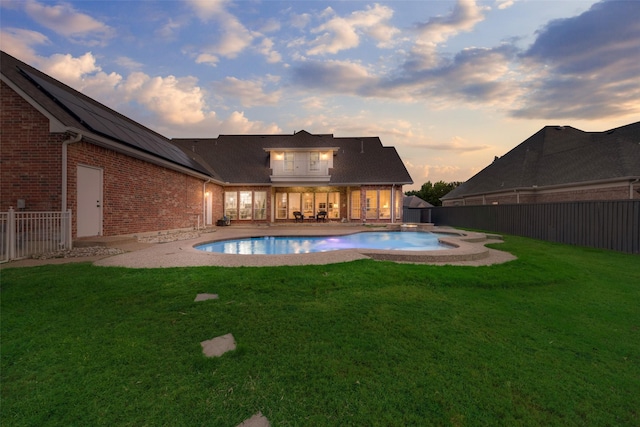 pool at dusk featuring a patio and a yard