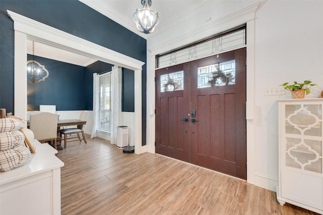 entrance foyer with hardwood / wood-style flooring, ornamental molding, and a chandelier