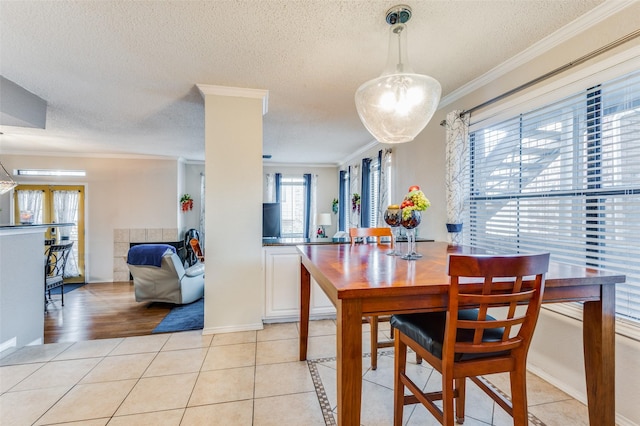 dining area with a textured ceiling, crown molding, and light tile patterned floors