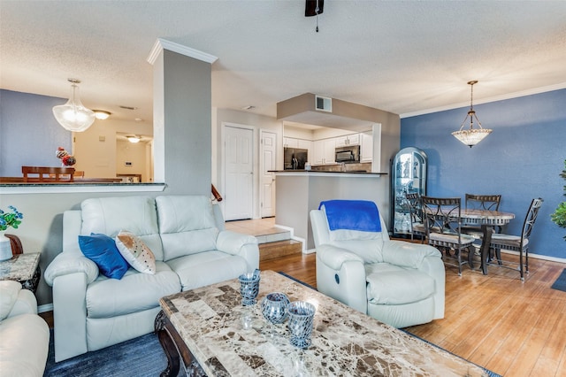 living room featuring a textured ceiling, crown molding, and hardwood / wood-style flooring