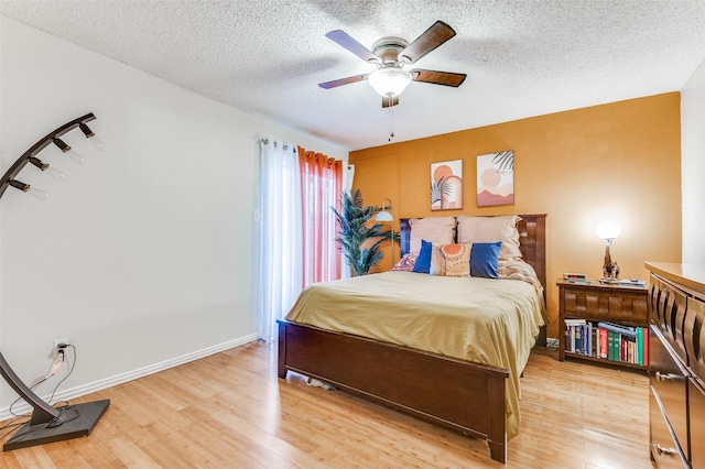 bedroom with a textured ceiling, ceiling fan, and hardwood / wood-style floors