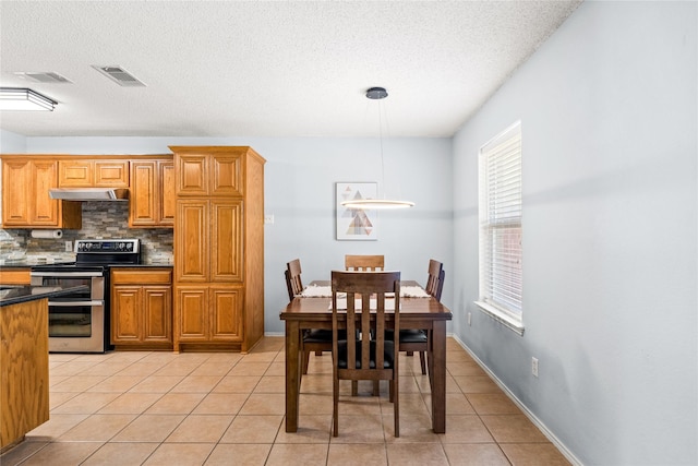 kitchen featuring range with two ovens, decorative light fixtures, light tile patterned flooring, and tasteful backsplash