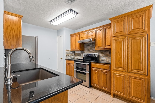 kitchen with stainless steel appliances, sink, dark stone countertops, light tile patterned floors, and decorative backsplash