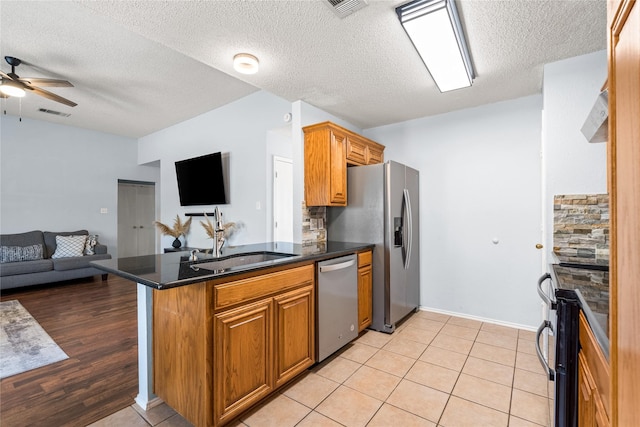 kitchen with kitchen peninsula, stainless steel appliances, light tile patterned floors, ceiling fan, and sink