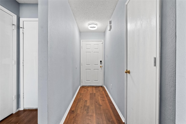 corridor featuring a textured ceiling and dark hardwood / wood-style floors