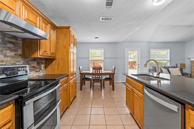 kitchen featuring stainless steel appliances, dark stone counters, a textured ceiling, sink, and light tile patterned flooring