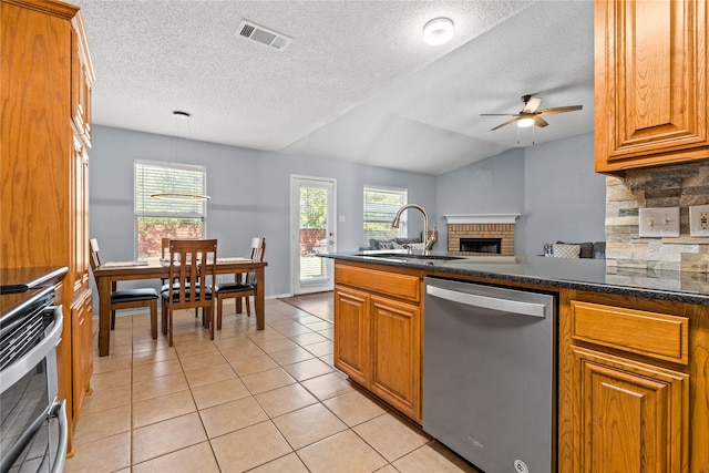 kitchen featuring stainless steel appliances, lofted ceiling, a brick fireplace, ceiling fan, and sink