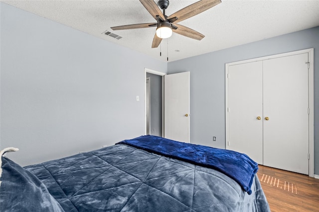 bedroom with hardwood / wood-style flooring, a textured ceiling, ceiling fan, and a closet