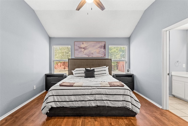 bedroom with ensuite bathroom, ceiling fan, vaulted ceiling, and multiple windows