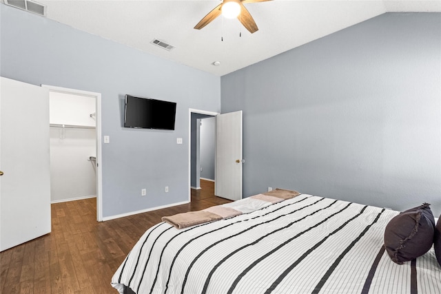 bedroom with dark wood-type flooring, a closet, lofted ceiling, a walk in closet, and ceiling fan