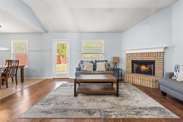 living room with lofted ceiling, a fireplace, a wealth of natural light, and dark hardwood / wood-style floors