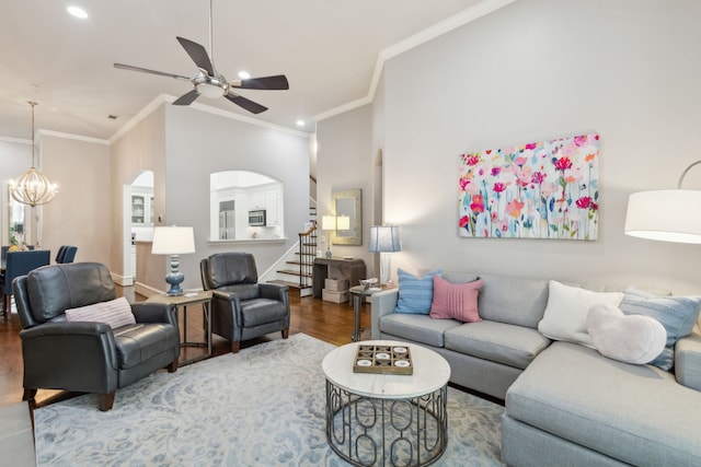 living room with ceiling fan with notable chandelier, crown molding, and wood-type flooring