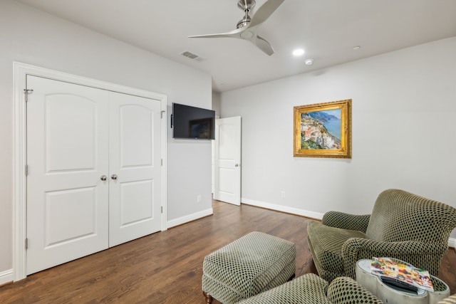 sitting room with ceiling fan and dark wood-type flooring