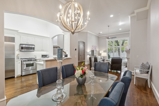 dining room featuring ceiling fan with notable chandelier, dark wood-type flooring, and crown molding