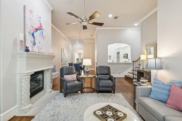 living room with ceiling fan with notable chandelier, hardwood / wood-style flooring, and ornamental molding