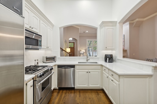 kitchen featuring kitchen peninsula, high end appliances, dark hardwood / wood-style flooring, white cabinetry, and sink