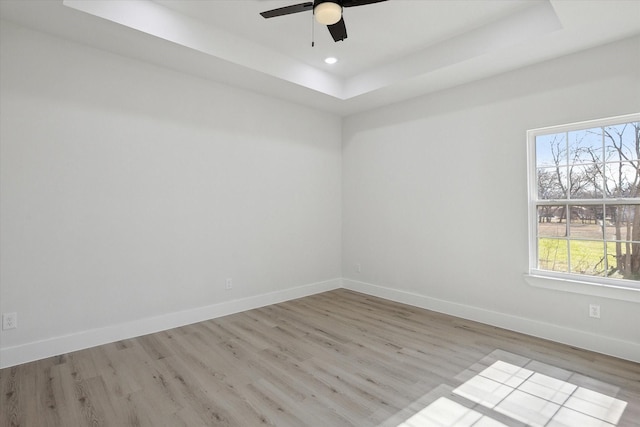 spare room featuring ceiling fan, a tray ceiling, and light hardwood / wood-style flooring