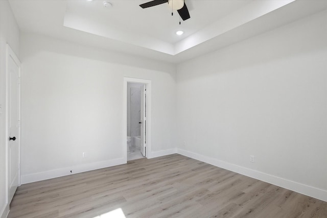 unfurnished room featuring ceiling fan, light hardwood / wood-style flooring, and a raised ceiling