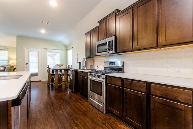 kitchen with tasteful backsplash, lofted ceiling, sink, stainless steel appliances, and dark brown cabinets