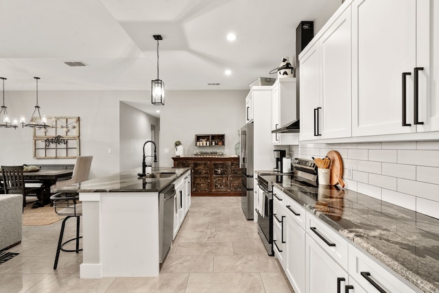 kitchen featuring white cabinets, a kitchen island with sink, stainless steel appliances, hanging light fixtures, and sink