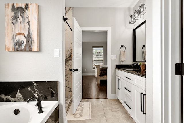 bathroom with a tub to relax in, tile patterned floors, and vanity