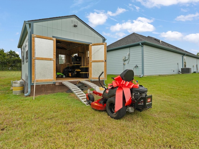 view of outdoor structure featuring central AC unit and a yard