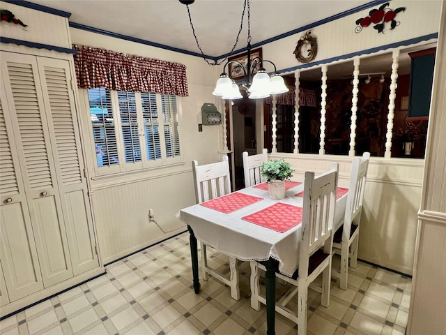 dining area with wooden walls, a notable chandelier, and crown molding